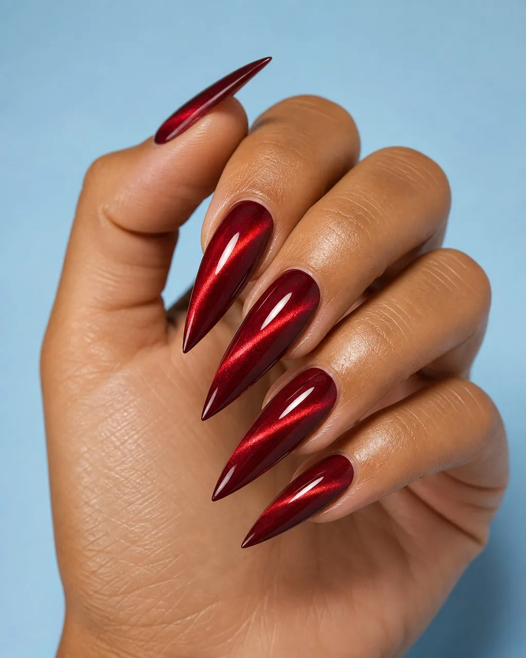 Garnet Cat-Eye — stiletto christmas nails with deep garnet red magnetic cat-eye gel with a sharp diagonal flash, glossy seal, long stiletto