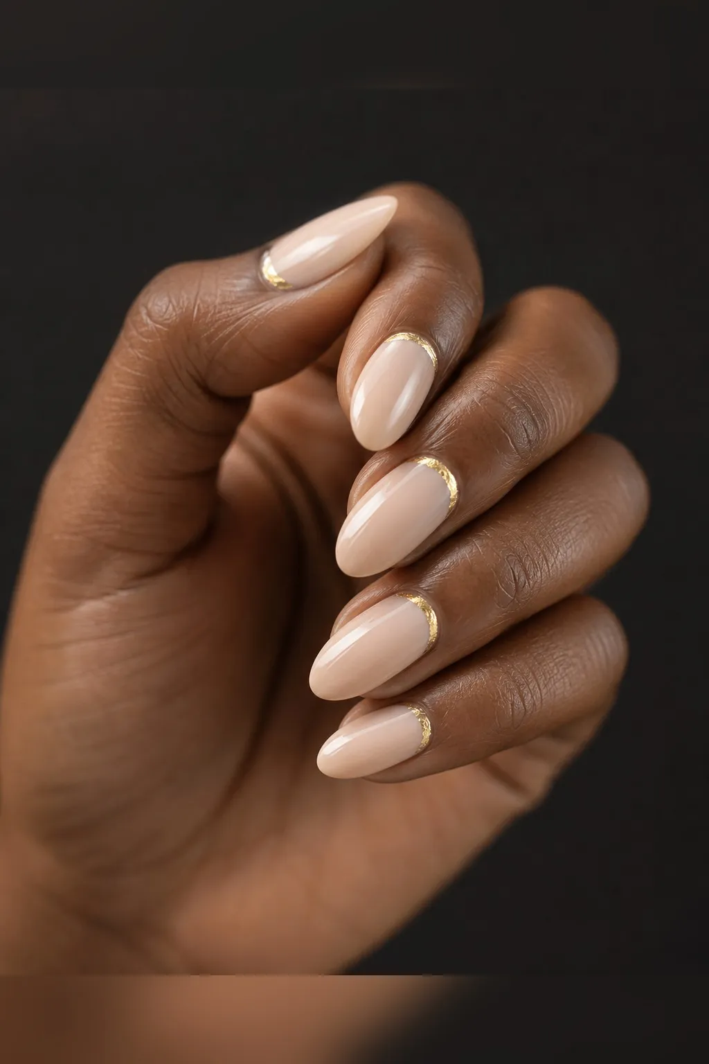 Gilded Cuticle Nude — almond christmas nails with sheer nude base with a thin gold foil crescent along the cuticle line on every nail…