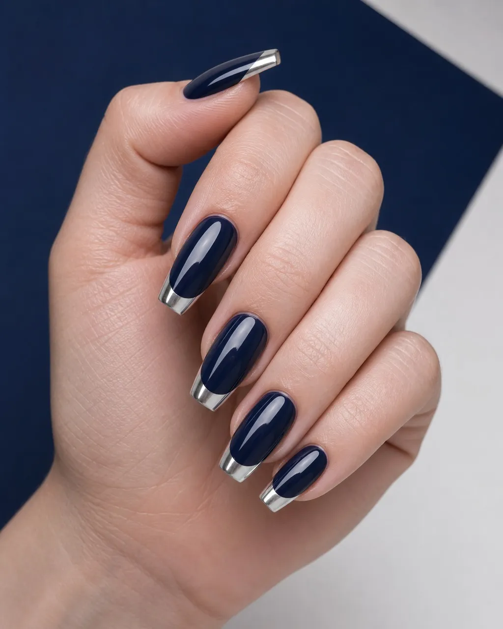Silver Bell French — coffin christmas nails with deep navy base with silver mirror-chrome french tips along a crisp smile line, glossy…