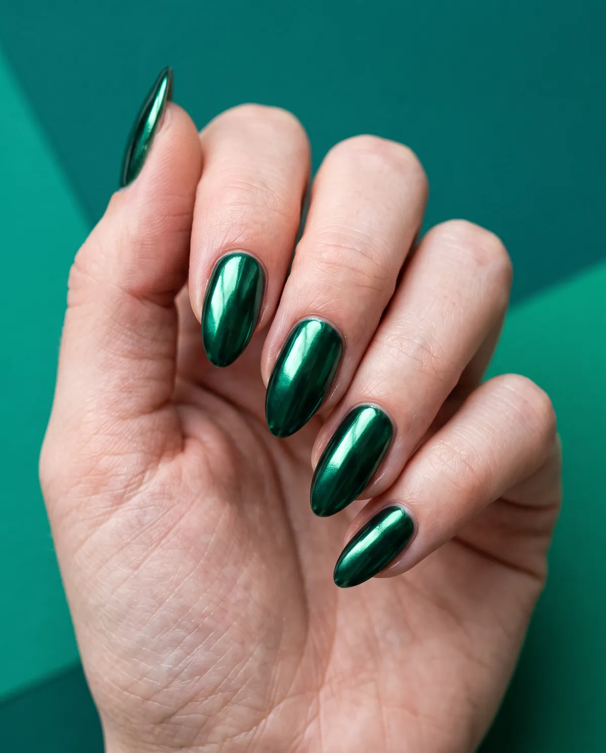 Emerald Mirror — almond chrome nails with deep green gel base with emerald chrome powder, glossy sealed top coat, almond shape