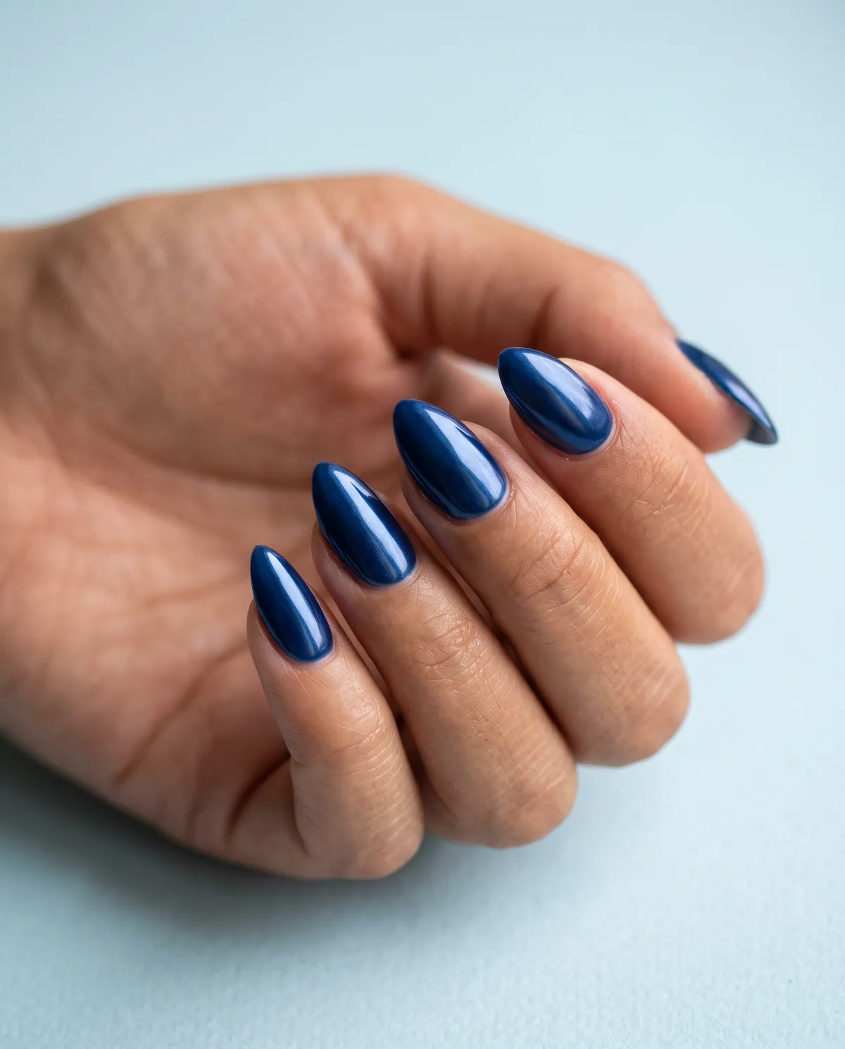 Sapphire Steel — stiletto chrome nails with deep blue gel base with sapphire chrome powder, sealed high-gloss top coat, long stiletto shape