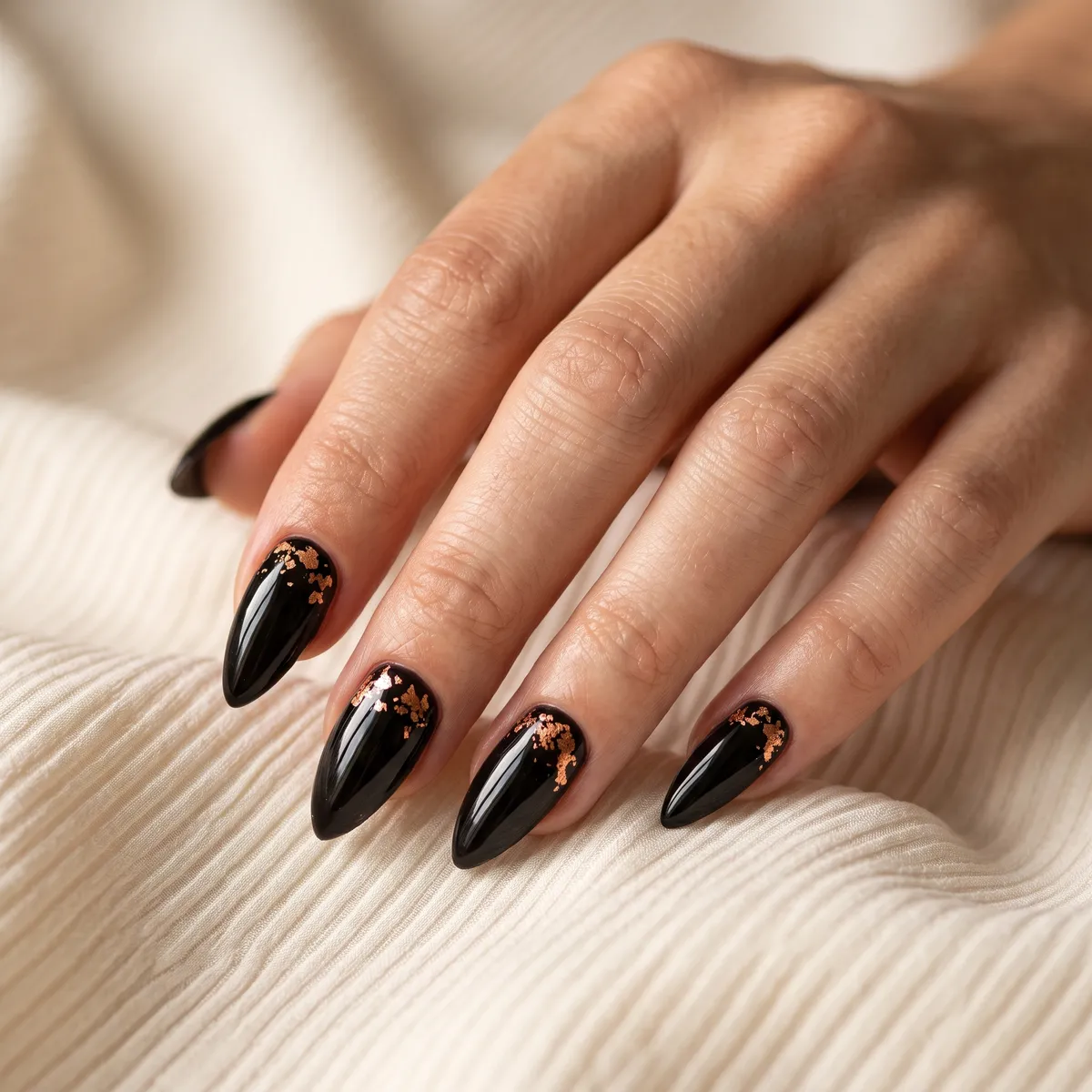 Copper Coven Foil — stiletto halloween nails with scatter copper foil flecks near the cuticle over a black gel base on stiletto nails, glossy…