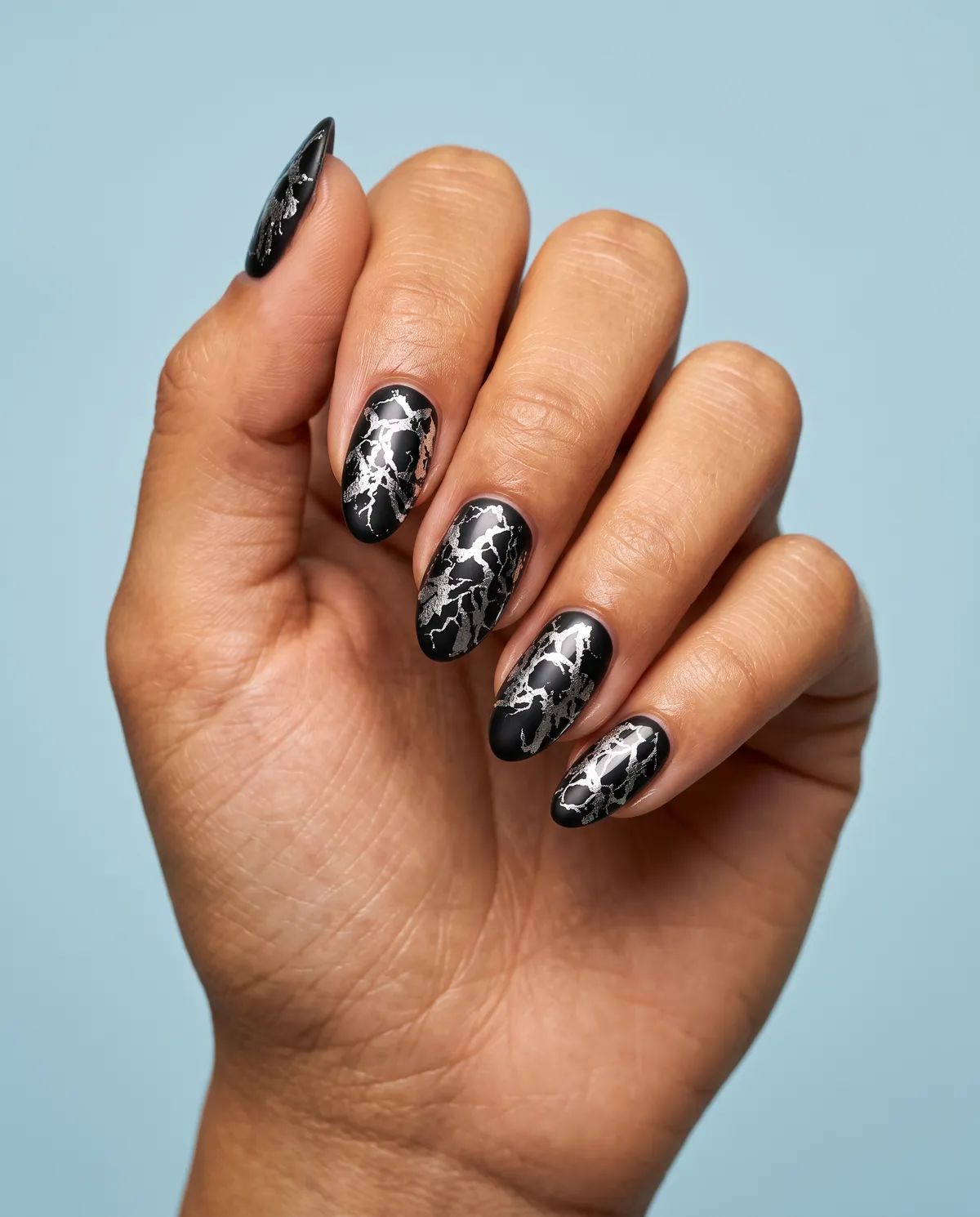 Foil Fracture Web — almond halloween nails with press silver foil in a cracked web pattern over a matte black base on almond nails, seal with…