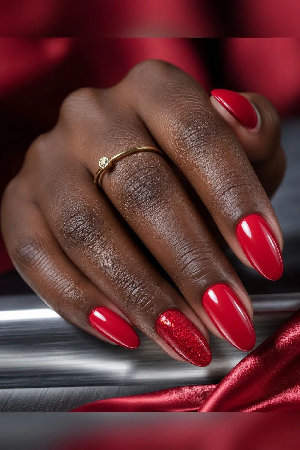 Red Glitter Accent — almond red nails with glossy true red crème on every nail, with fine matching red glitter on the ring fingers only…