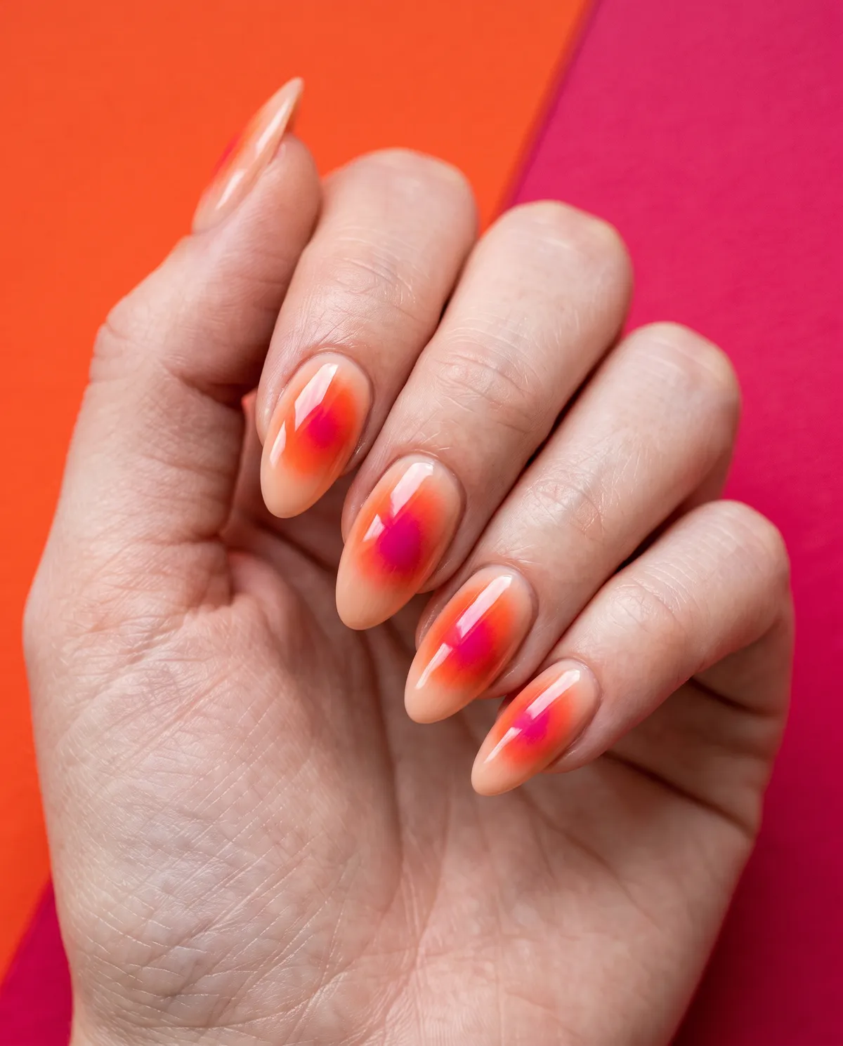 Sunset Aura — almond red nails with i'd like a nude base with an airbrushed orange-red and pink aura in the center, almond shape