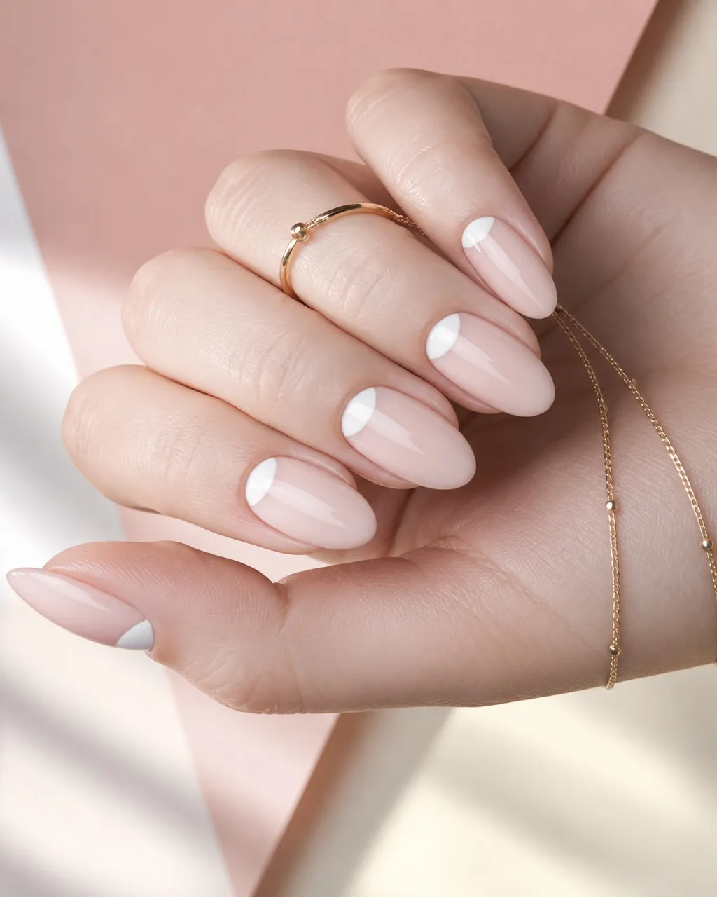 Reverse French — almond french nails with sheer milky base with a crisp white half-moon at the cuticle instead of the tip, glossy, medium almond